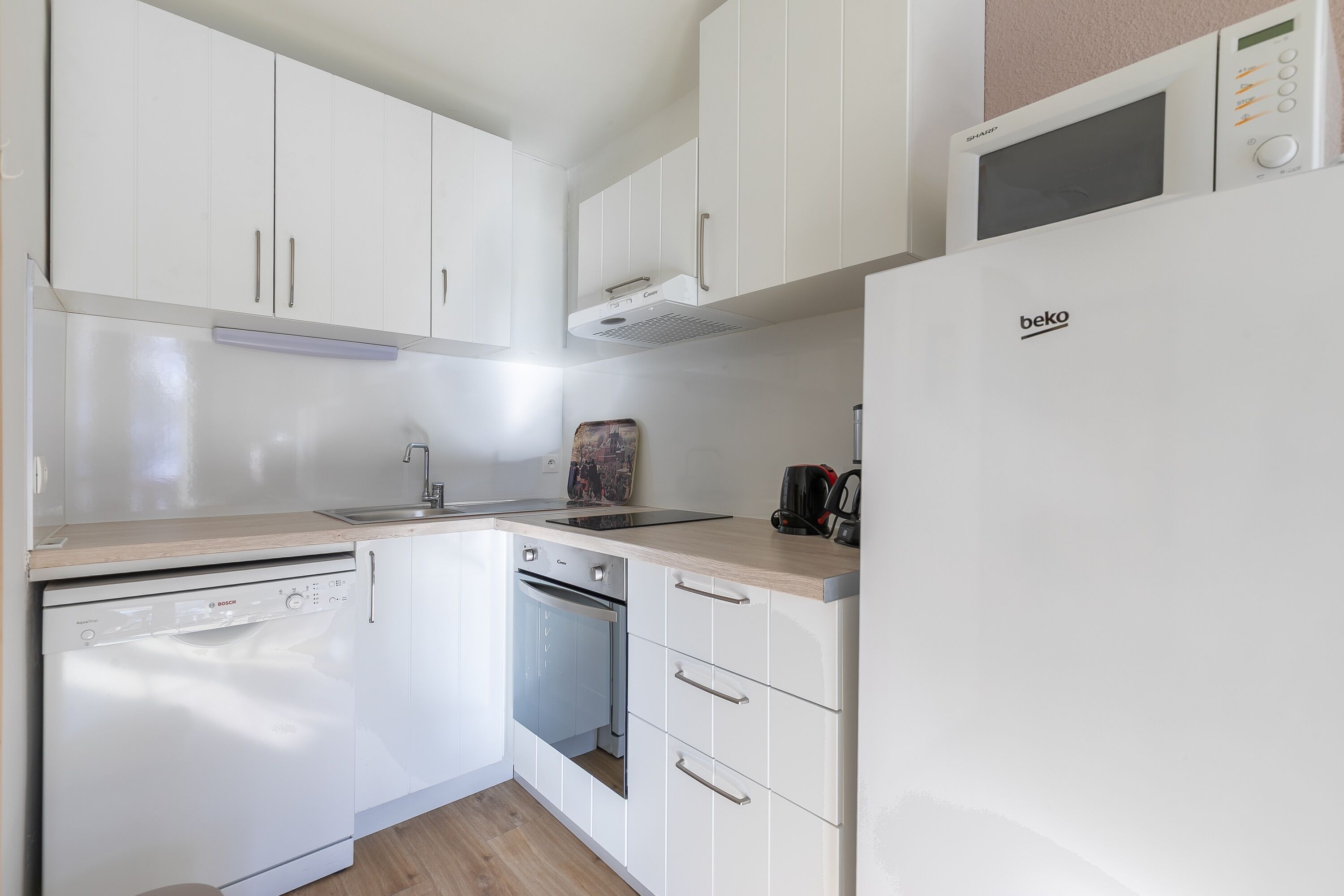 A compact kitchen with white cabinets, a built-in microwave, a dishwasher, and a stove.