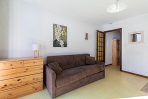 Un salon avec un canapé marron, une commode en bois et un tableau accroché au mur.