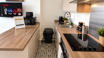 Cocina moderna con microondas integrado, cafetera y campana extractora de acero inoxidable.