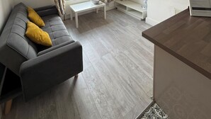 A modern living room with a grey sofa, a small white table, a TV, and a window with curtains. - Newly Redecorated 1 bed flat ! (Weston-Super-Mare)