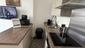 A compact kitchen with a microwave, sink, and stove. There's a small trash bin and a decorative sign on the counter. - Newly Redecorated 1 bed flat ! (Weston-Super-Mare)