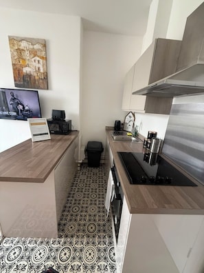 A compact kitchen with a microwave, sink, and stove. There's a small trash bin and a decorative sign on the counter. - Newly Redecorated 1 bed flat ! (Weston-Super-Mare)