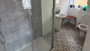 A bathroom with a glass shower enclosure, a sink, a toilet, and patterned floor tiles. - Newly Redecorated 1 bed flat ! (Weston-Super-Mare)