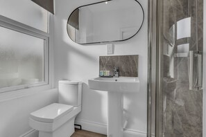 Un baño con inodoro, lavamanos y ducha.