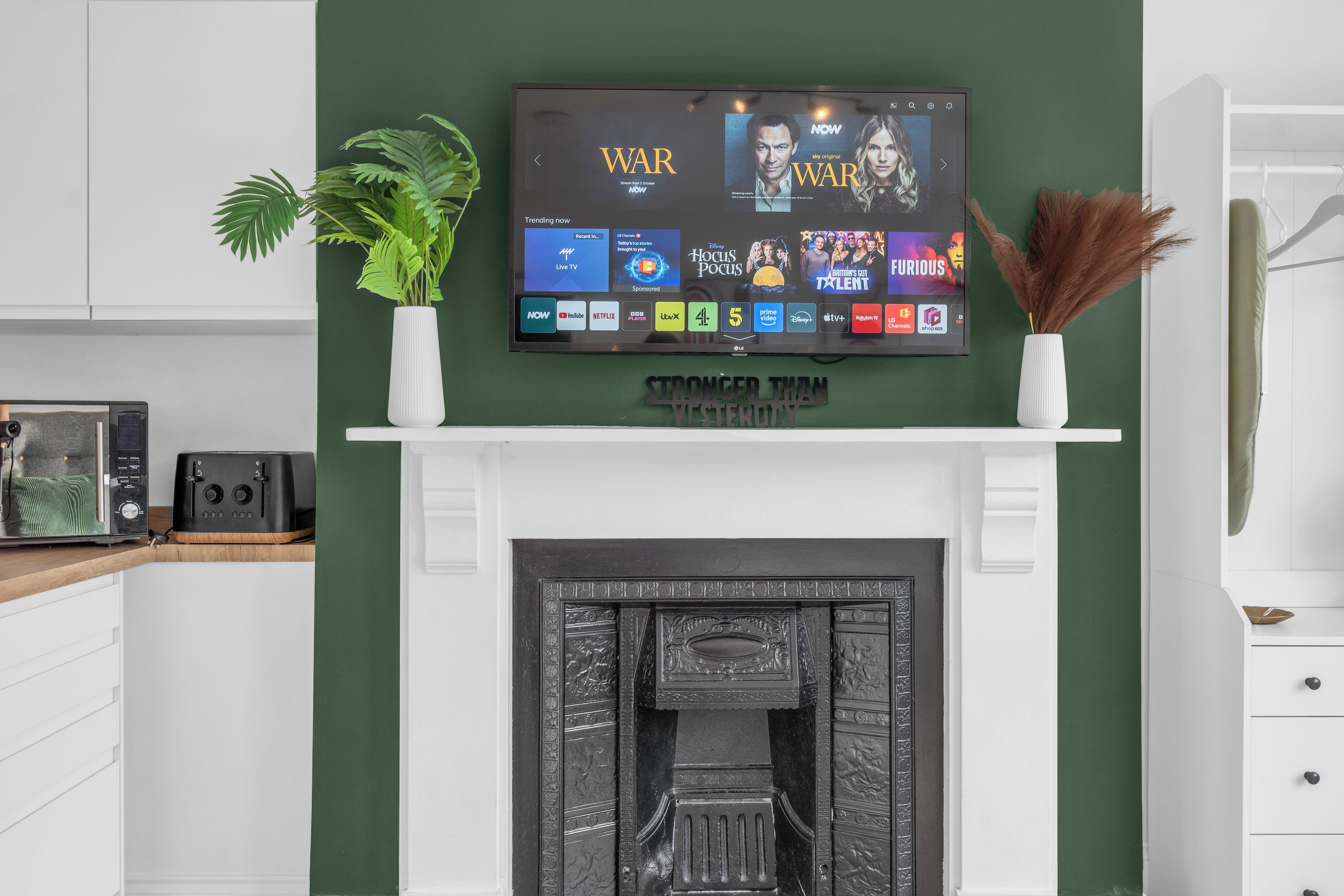 Un saló modern amb un televisor de pantalla plana penjat sobre una llar de foc, una planta en test i elements decoratius.