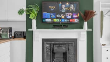Un saló modern amb un televisor de pantalla plana penjat sobre una llar de foc, una planta en test i elements decoratius.