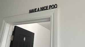 Een deur met een bord waarop staat 'HAVE A NICE POO'.