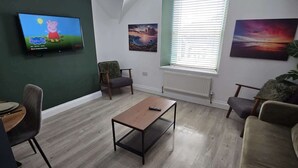 Un saló modern amb televisió plana, una taula de centre i un sofà.