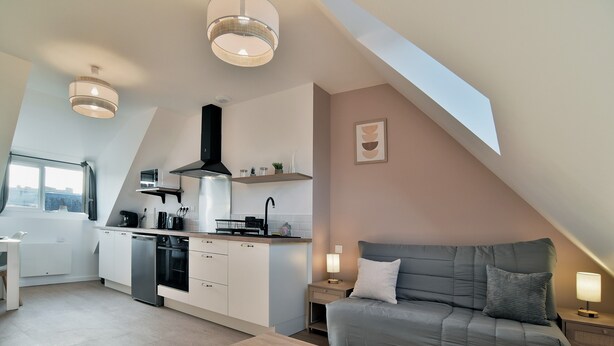 A modern loft apartment with a kitchen, dining area, and a cozy living space with a sofa and a coffee table.