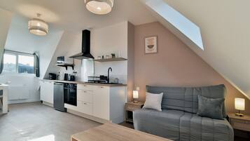 Un appartement moderne de style « loft », comprenant une cuisine, un coin repas et un espace de vie confortable avec un canapé et une table basse.