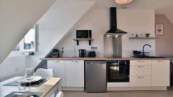 Une cuisine moderne avec des meubles blancs, un lave-vaisselle, un four à micro-ondes et une cuisinière.