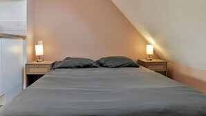 A bedroom with a bed, two bedside tables with lamps, a wall-mounted shelf, and a ceiling light.