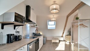 A modern kitchen with a microwave, toaster, and kettle on the counter, a built-in oven, and a window above the sink.