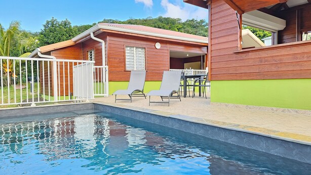 A wooden building with a swimming pool, a fenced area, and a table with chairs. - Villa with private swimming pool, quiet and friendly stay (Le Vauclin)