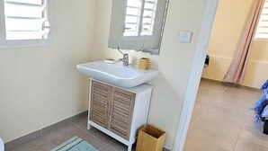 A small bathroom with a toilet, sink, and mirror. - Villa with private swimming pool, quiet and friendly stay (Le Vauclin)