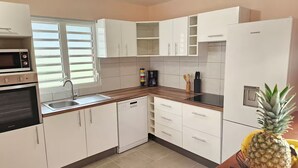 A modern kitchen with white cabinets, a microwave, a dishwasher, and a refrigerator. - Villa with private swimming pool, quiet and friendly stay (Le Vauclin)