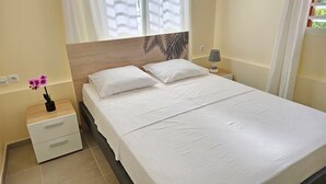 A neatly made bed with white linens, a wooden headboard, a bedside table with a lamp, and a small potted plant. - Villa with private swimming pool, quiet and friendly stay (Le Vauclin)