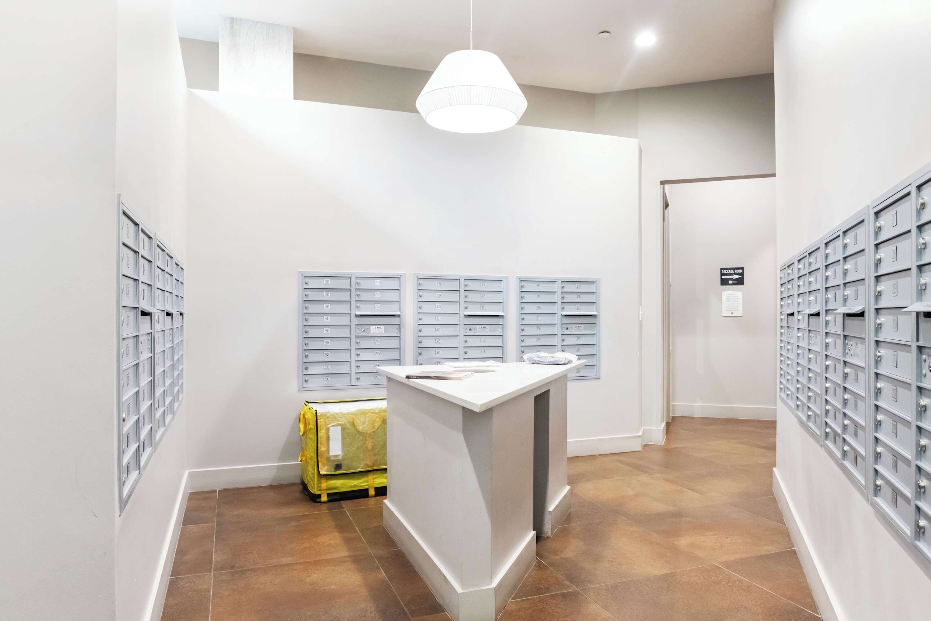 Een nette, moderne lobby met een receptiebalie, opslagkasten en een gele koffer.