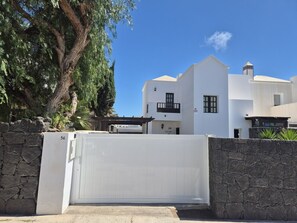 A white building with a stone wall and a gate. - Villa Adel: Oasis de paz con piscina climatizada (Playa Blanca)