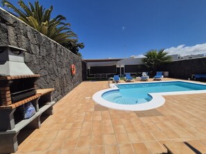 En swimmingpool med en mur av sten och ett område för grillning.