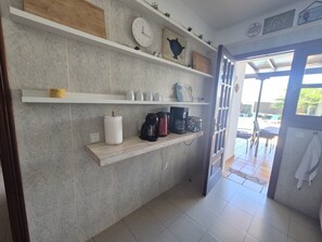 A kitchen with white shelves, a clock, and a coffee maker. - Villa Adel: Oasis de paz con piscina climatizada (Playa Blanca)