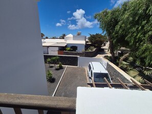 Zona residencial con una camioneta blanca estacionada en una entrada, rodeada de vegetación y un cielo despejado.