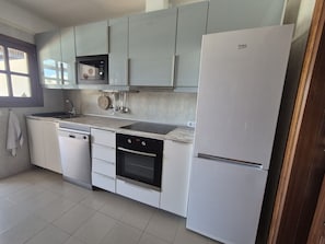 Una cocina moderna con armarios blancos, horno integrado, microondas y refrigerador.