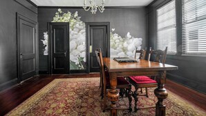 A dining room with a wooden table, chairs, and a red upholstered bench. There are two doors and a chandelier. - Emma’s Cottage on Madison Avenue (Montgomery)