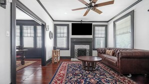 A living room with a brown leather sofa, a round coffee table, and a patterned rug. - Emma’s Cottage on Madison Avenue (Montgomery)