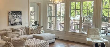 A spacious living room with a large sectional sofa, a massage chair, and a chandelier.