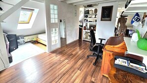 Un loft spacieux avec un plafond haut, un plancher en bois et une lucarne.