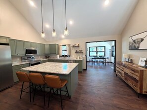 Una cucina con mobili verdi, un'isola grande con sedie e un'area pranzo con tavolo e sedie.
