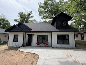 A two-story house with a black roof, white siding, and a number '30275' on the door.