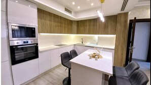 Une cuisine moderne dotée d’appareils électroménagers intégrés, d’un îlot central et de tabourets de bar.