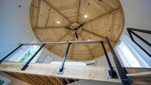 A wooden ceiling with a central fan and a staircase with metal railings.