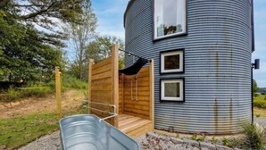 A cylindrical metal building with a wooden deck and a metal tub.
