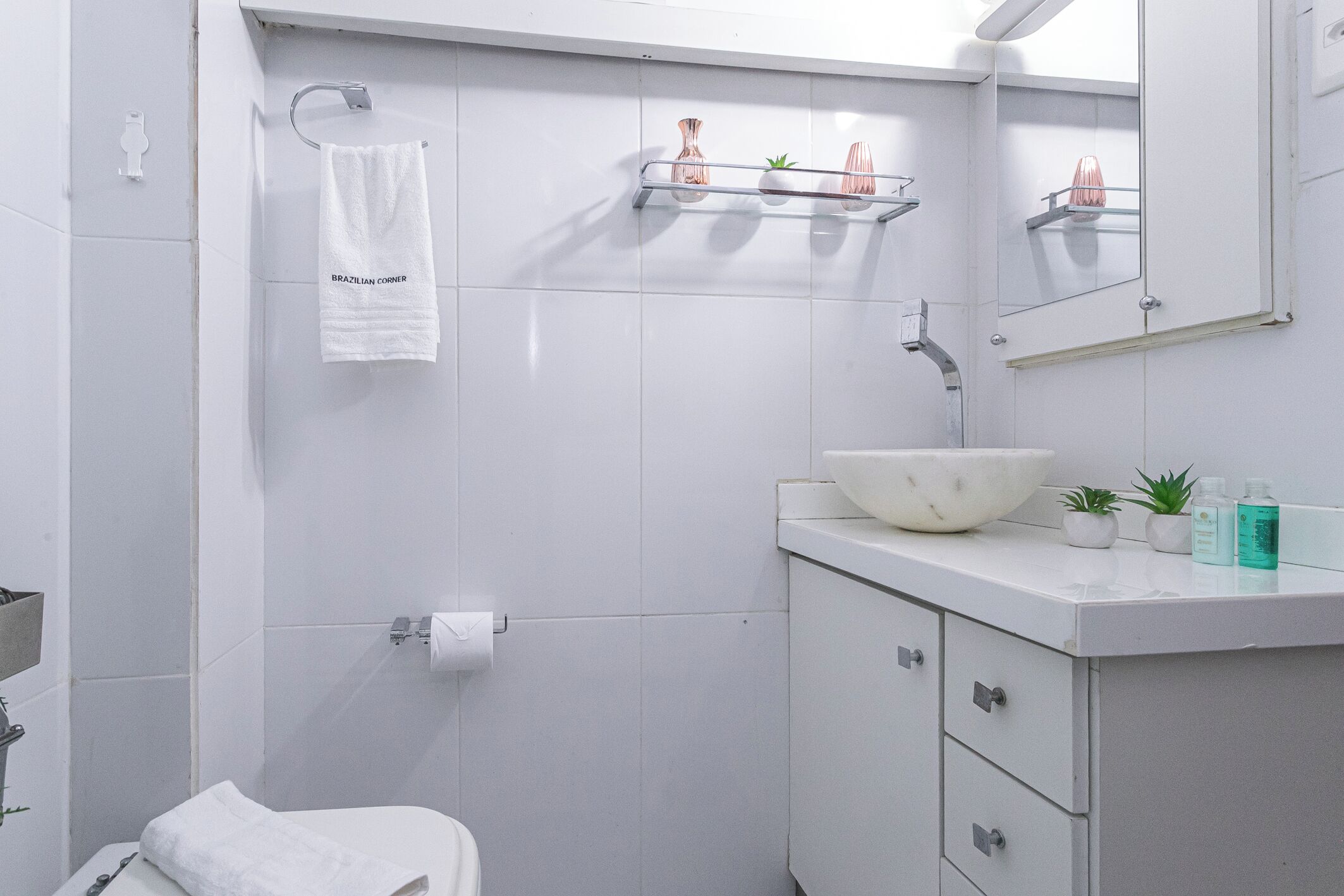 A modern bathroom with a white sink, vanity, and towel rack.
