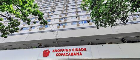 Um edifício de vários andares com a placa 'Shopping Cidade Copacabana'.