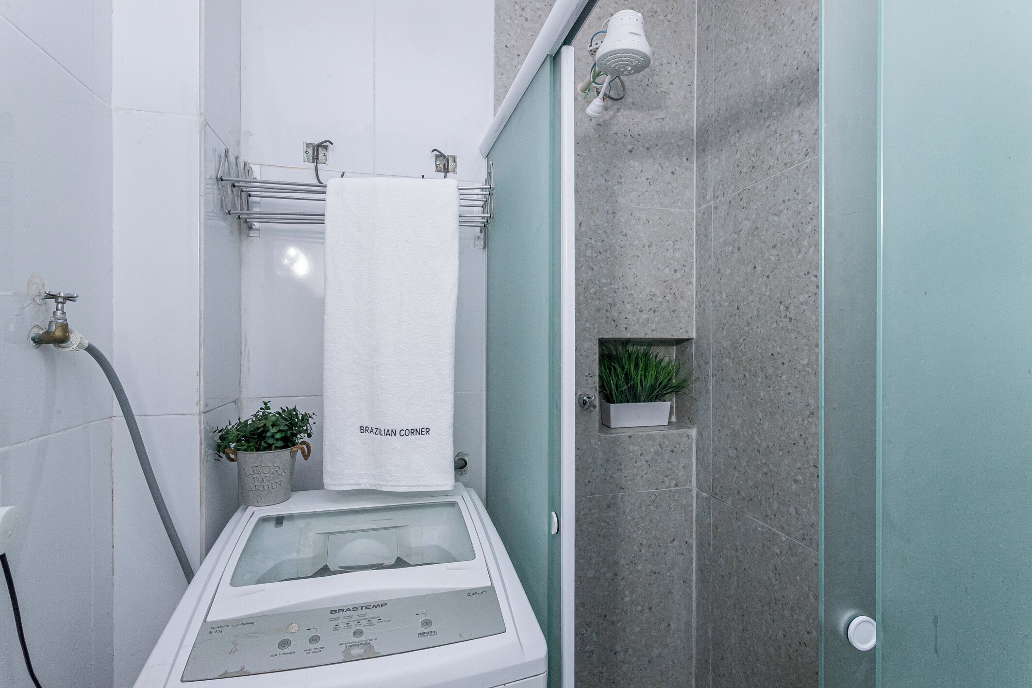 Une salle de bain équipée d’une douche à vapeur, d’un porte-serviettes, d’une plante en pot et d’un générateur de vapeur.