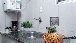A kitchen with a stainless steel sink, a coffee maker, potted plants, and a basket of bread. - Incredible view of Cristo Redentor (Rio de Janeiro)