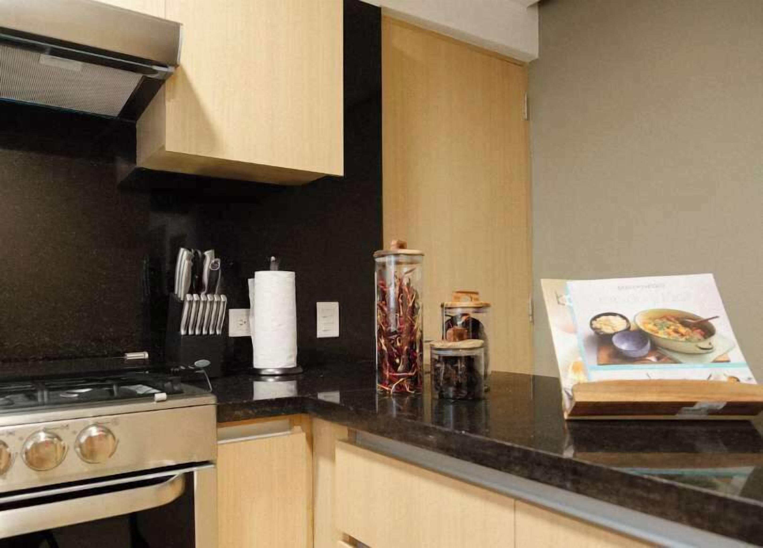 Une cuisine équipée d’une cuisinière, de placards et d’un livre de recettes posé sur le plan de travail.