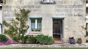 Un edificio de piedra con puerta, ventanas y plantas en macetas.