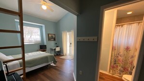 Une chambre avec un lit superposé, un bureau, une chaise et une fenêtre avec des stores.