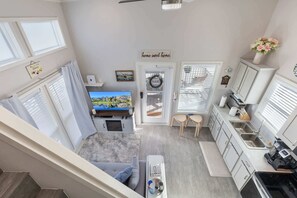 A compact living space with a TV, kitchenette, and a cozy seating area. - Longhorn Villa (Fredericksburg)