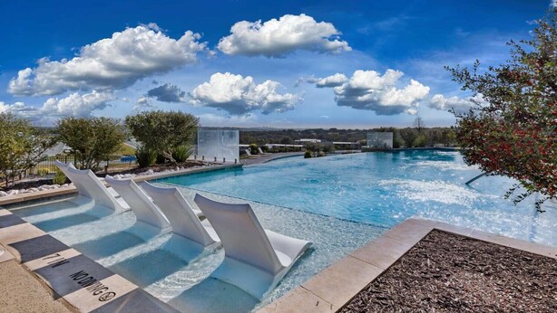 Una piscina con toboganes, cielo despejado y árboles a lo lejos.