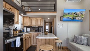 Una cocina con armarios de madera, una isla central y una zona de comedor con un sofá y taburetes.