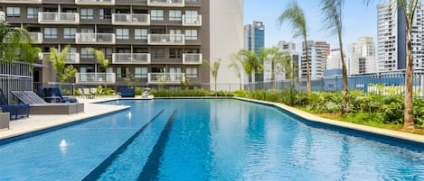 Une piscine à l’eau d’un bleu cristallin, entourée d’une basse clôture et d’une végétation luxuriante.