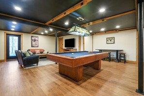 A pool table in a room with wooden floors, a television, and a large window. - Brawny Woods | Hocking Hills, Hot Tub, Fireplace (South Bloomingville)