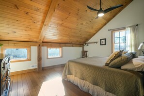 A bedroom with a wooden ceiling, a bed with a quilted bedspread, a dresser, and a window with curtains. - Brawny Woods | Hocking Hills, Hot Tub, Fireplace (South Bloomingville)