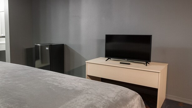 A hotel room with a bed, a TV on a wooden stand, and a black refrigerator. - 112 Gated 2 Queen Beds Hotel Room (Jackson)